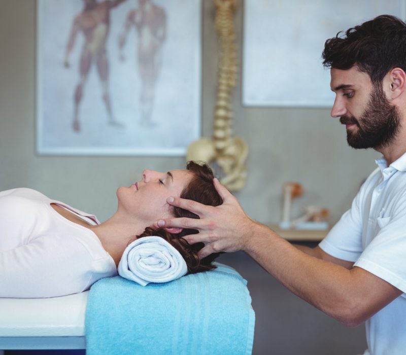Physiotherapist giving head massage to a woman in clinic